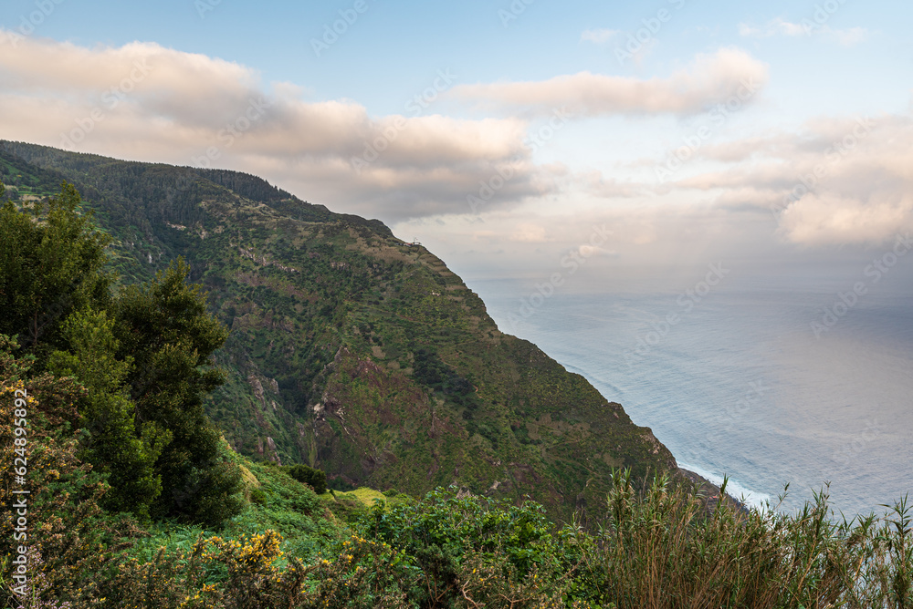 Atlantic Ocean with steep partly rocky hills above in northwestern coast of Madeira island
