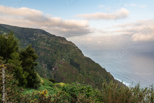 Atlantic Ocean with steep partly rocky hills above in northwestern coast of Madeira island