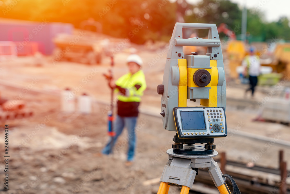 Fototapeta premium Female site engineer surveyor working with theodolite total station EDM equipment on a building construction site outdoors