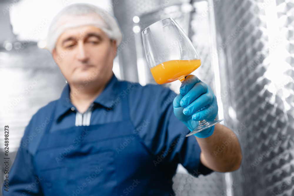 Worker on brewery, man quality control mead beer in wineglass background tanker Worker on brewery, man quality control mead beer in wineglass background tanker