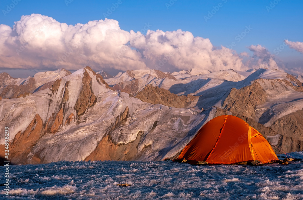 Tent camp on the ice top of the peak with stunning mountain views at sunset; concept of outdoor activities in the wild