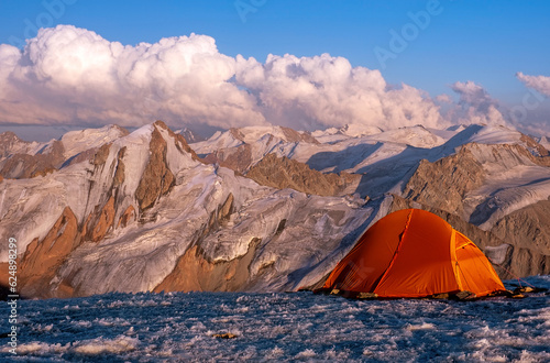 Tent camp on the ice top of the peak with stunning mountain views at sunset  concept of outdoor activities in the wild © kiwisoul