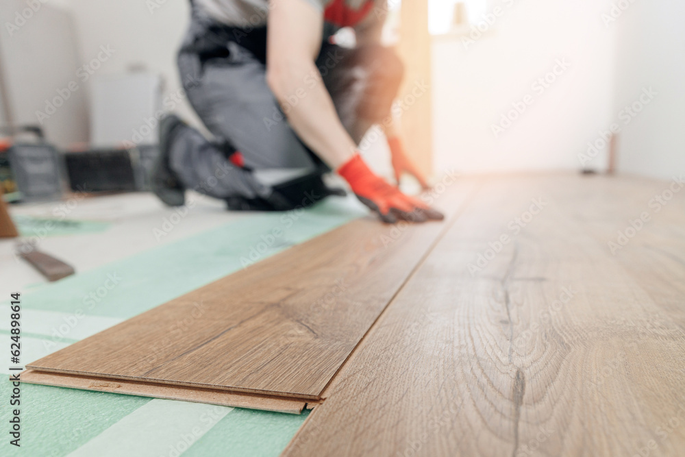 Professional worker Installing laminated or wood parquet on floor, man holding wooden tile Professional worker Installing laminated or wood parquet on floor, man holding wooden tile