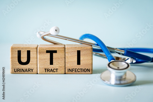 Obraz na płótnie Medical stethoscope and wooden blocks with the medical abbreviation UTI for Urinary Tract Infection, Medical concept, beautiful blue background w salonie
