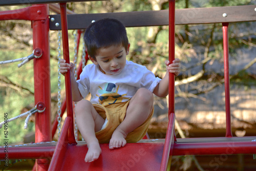 two year old boy playing in a park, wearing a diaper under his pants, comfort concept