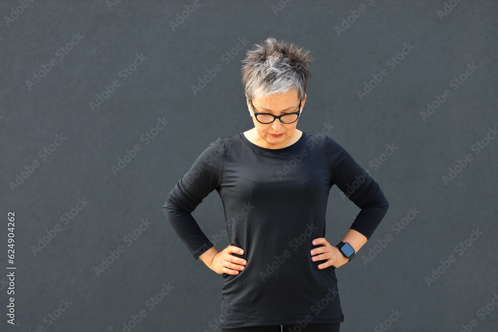 Relaxed gray-haired mature woman in sportswear after morning workout.