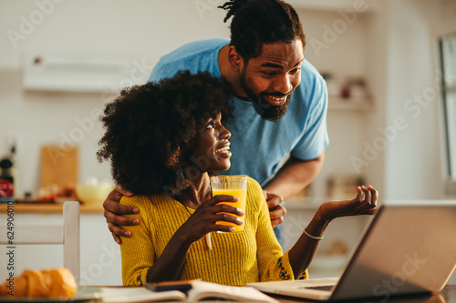 Tablou pe pânză An African American casual businesswoman is taking a break from a remote job on a laptop and taking advice from her supportive husband
