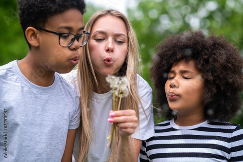 Blonde girls and two african american kids blowing on dandelion
