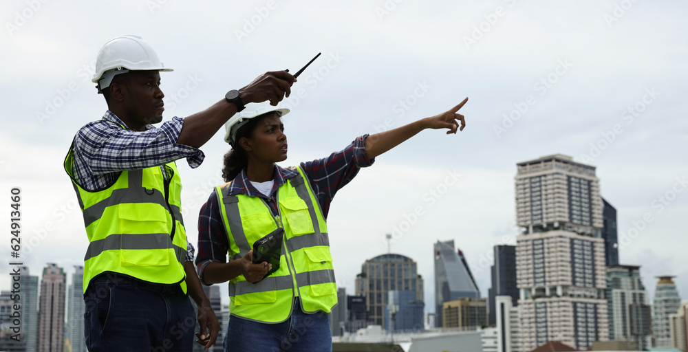 Male and Female engineer team working on the rooftop of a high building in City Male and Female engineer team working on the rooftop of a high building in City