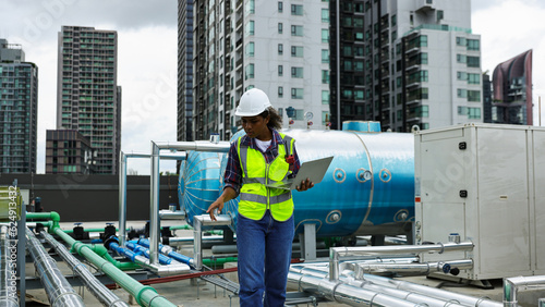 Female environment engineer with safety uniform with walkie-talkie using a smartphone working on the sideline