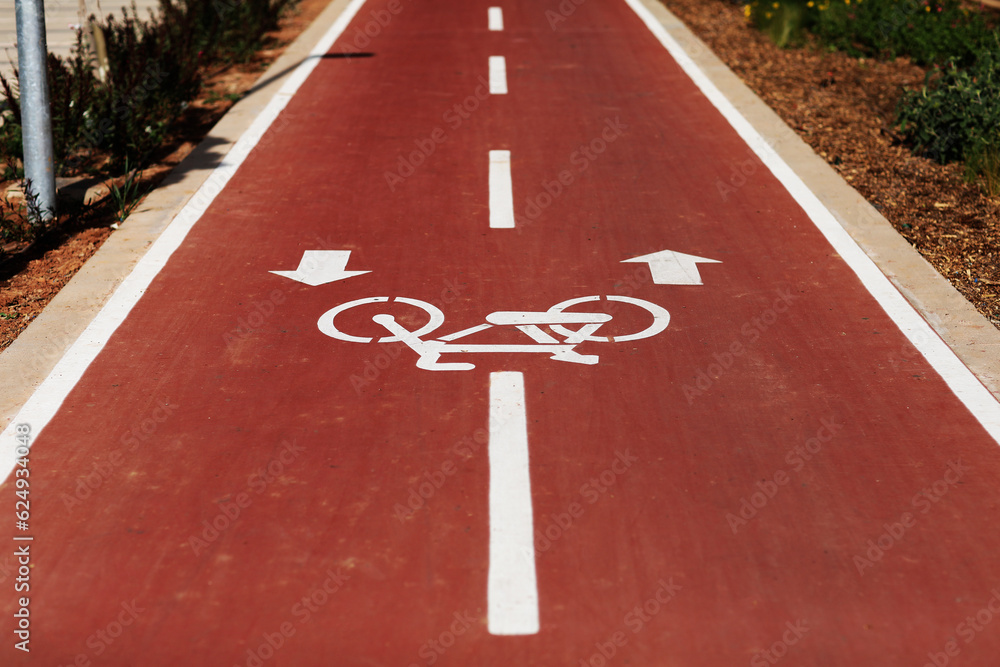 Fototapeta premium New marking bike path. White bicycle symbol and two oposite arrows on red asphalt lane, road. Bicycle path in the city. Two-way cycle lane on an avenue. Lifestyle. Urban traffic and transportation