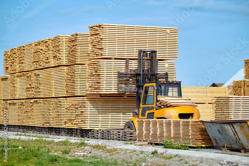 Fotografia Forklift loading lumber wood boards in stack, finished product warehouse ready for transportation