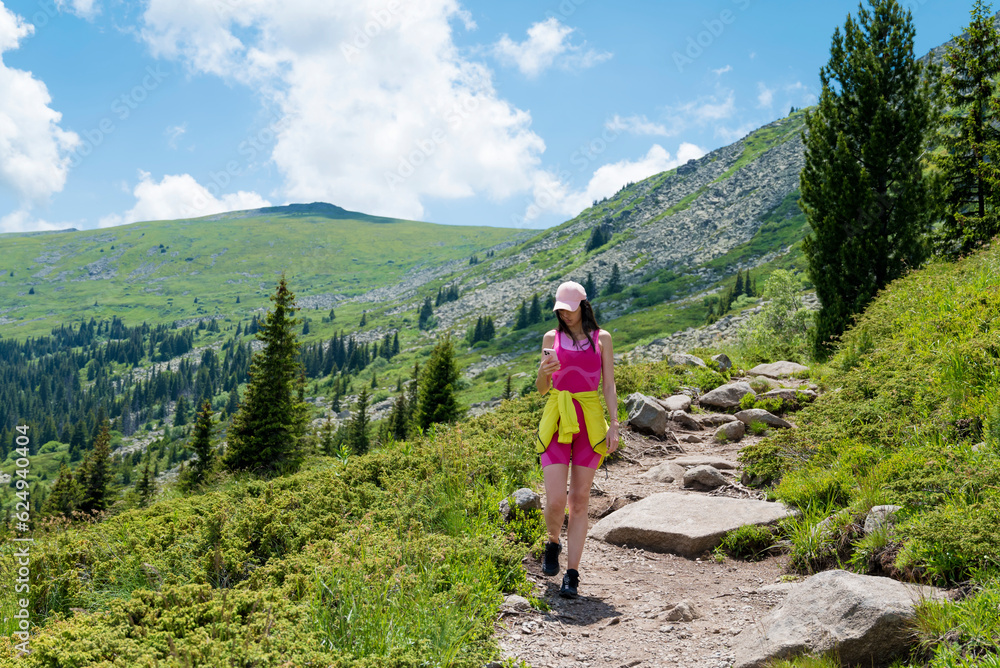 Young Woman using mobile phone in the Summer  Mountain .Woman using trail map in the mountain 