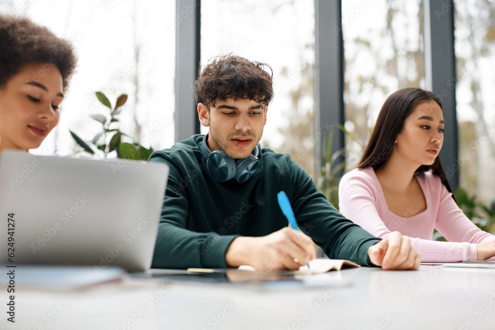 Study process concept. Multiracial students sitting at desk learning together, preparing for university exams Study process concept. Multiracial students sitting at desk learning together, preparing for university exams