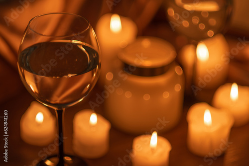 Lots of candles burning in the dark and two glasses of white wine. Romantic evening, date.