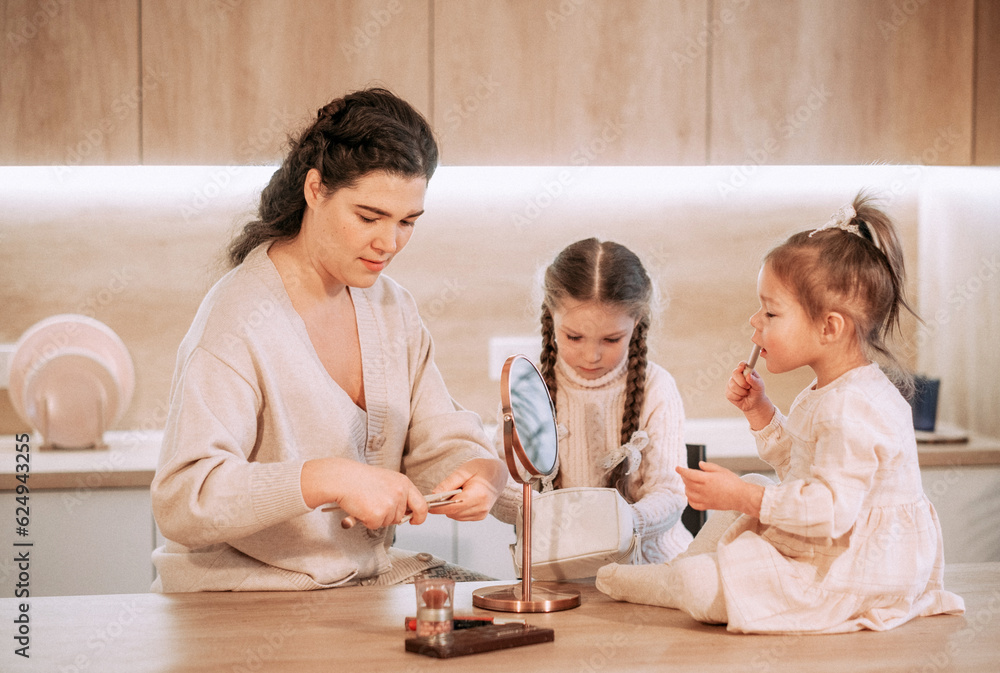 Two little girls sisters play with their mother using cosmetics. Makeup game. Happy time at home. Two little girls sisters play with their mother using cosmetics. Makeup game. Happy time at home.
