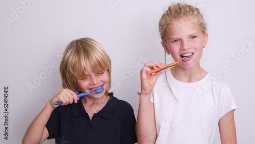 Portrait two kids having fun brushing teeth, happy smiling children kids boy and girl with toothbrush on white, looking at camera, Health care, dental hygiene. photo