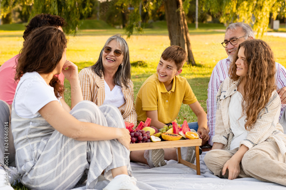 Happy european multi-generation family enjoy picnic, fruits, eat food in park, talk, outdoor