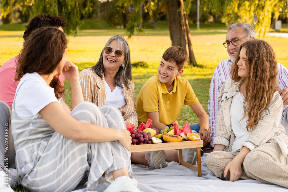 Happy european multi-generation family enjoy picnic, fruits, eat food in park, talk, outdoor Happy european multi-generation family enjoy picnic, fruits, eat food in park, talk, outdoor