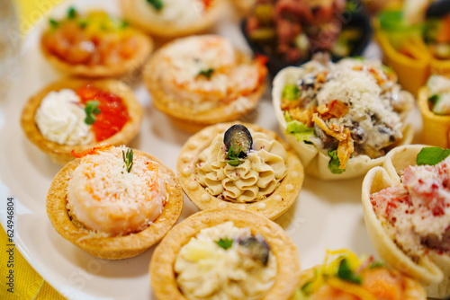 Canapes tartlets with various delicious fillings on a plate. photo
