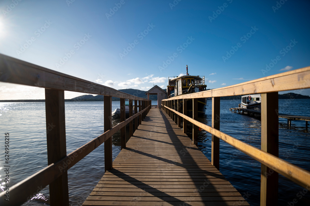 wooden bridge in the sea, Deck with wooden beach chairs to rest with calm and relaxing sea, boats in the background