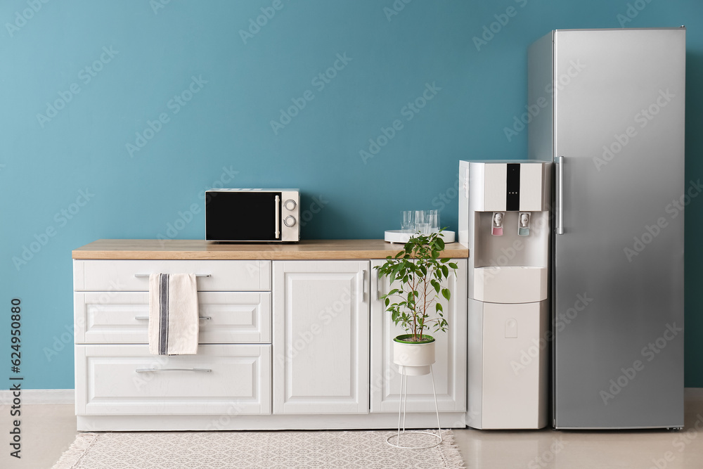 Interior of kitchen with modern water cooler near blue wall Interior of kitchen with modern water cooler near blue wall