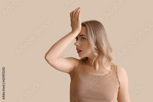 Young woman doing face building exercise on beige background