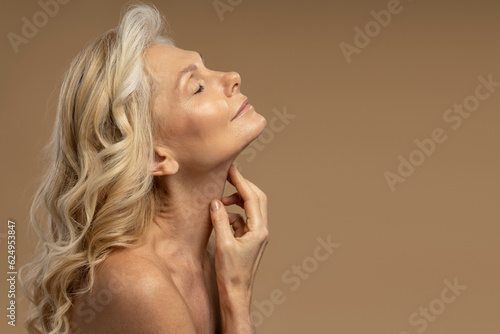 Beautiful blonde Caucasian 50-55 years mature woman posing with closed eyes isolated