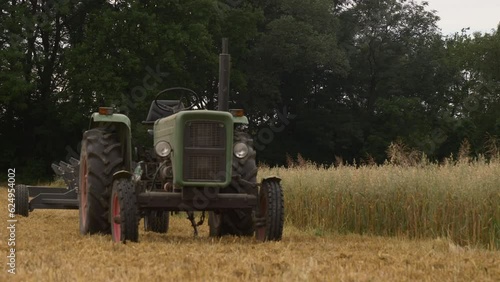 Wroclaw, Poland - 16 July 2023: Vintage green tractor stands on golden wheat field while harvest, Poland