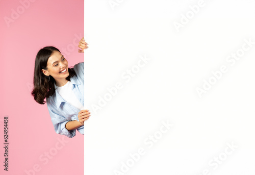 Excited beautiful lady looking at white empty placard