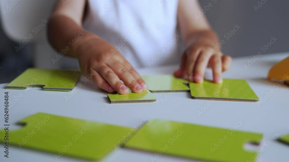Little hands of unrecognized baby playing with puzzles. Kid moves the pieces trying to connect them properly. Close up. Little hands of unrecognized baby playing with puzzles. Kid moves the pieces trying to connect them properly. Close up.