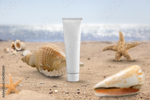 White tube bottle of sunscreen on golden sandy beach