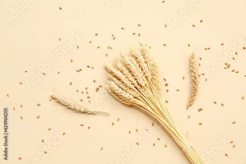 Bundle of wheat ears and grains on beige background photo
