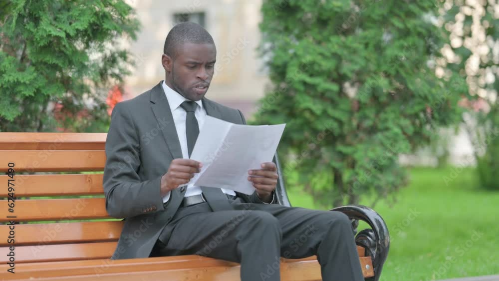African Businessman Reading Documents while Sitting Outdoor African Businessman Reading Documents while Sitting Outdoor