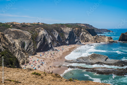 Rocky cliffs and silhouettes of people on the sand of Alteirinhos beach, Zambujeira do Mar - Odemira PORTUGAL photo