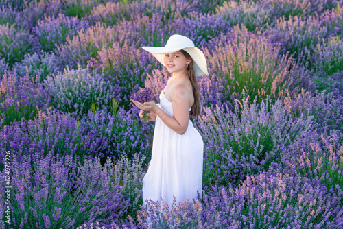 positive girl at lavender flowers in garden. Young girl in white dress walking through lavender flowers. lovely girl posing in lavender flowers. beautiful girl in lavender field surrounded by flowers