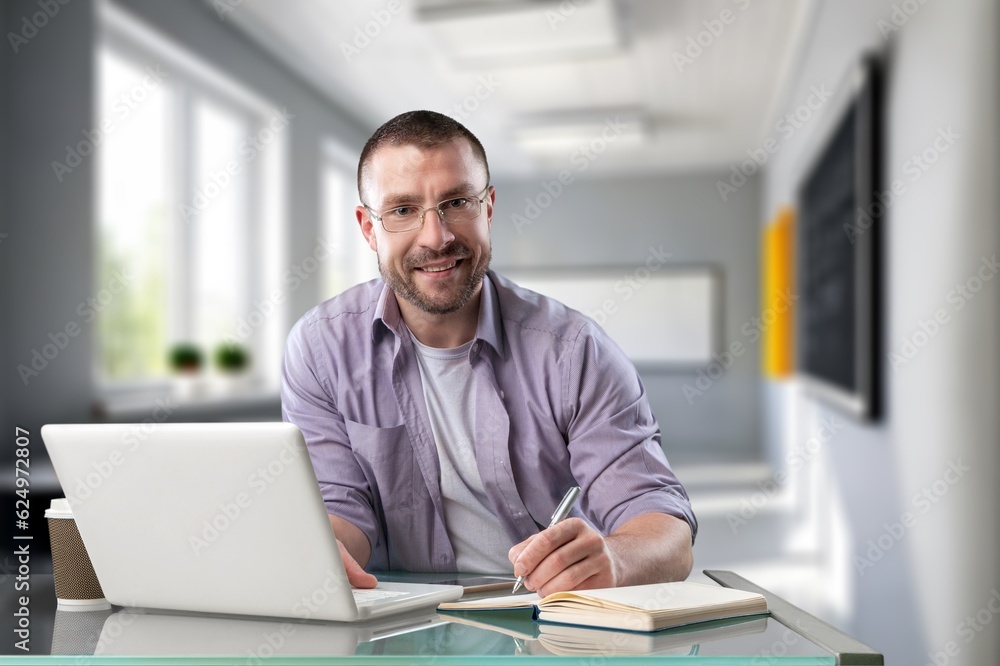Naklejka premium Young happy business person or teacher with laptop computer
