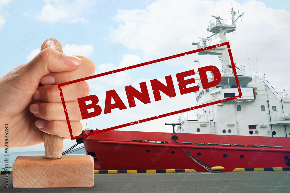 Obraz premium Economic sanctions. Woman holding ban stamp. Ship moored in port