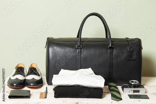 Duffel travel bag and traveler items on a white table