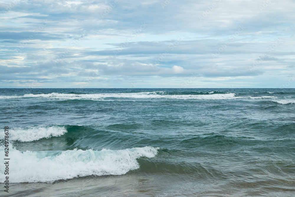 Vastidão do oceano com ondas no litoral do Brasil em uma tarde com nuvens. 