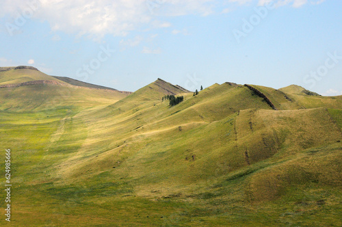 Parallel rows of stony formations running along the gentle slopes and tops of high hills on a sunny summer day.