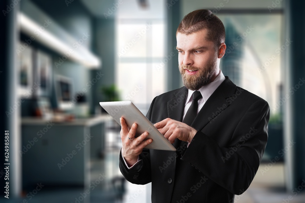 Handsome young businessman works on digital tablet Handsome young businessman works on digital tablet
