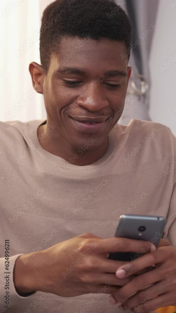 Vertical video. Mobile leisure. Gadget chatting. Internet browsing. Happy relaxed man texting message on smartphone enjoying online distance communication at home. Vertical video. Mobile leisure. Gadget chatting. Internet browsing. Happy relaxed man texting message on smartphone enjoying online distance communication at home.