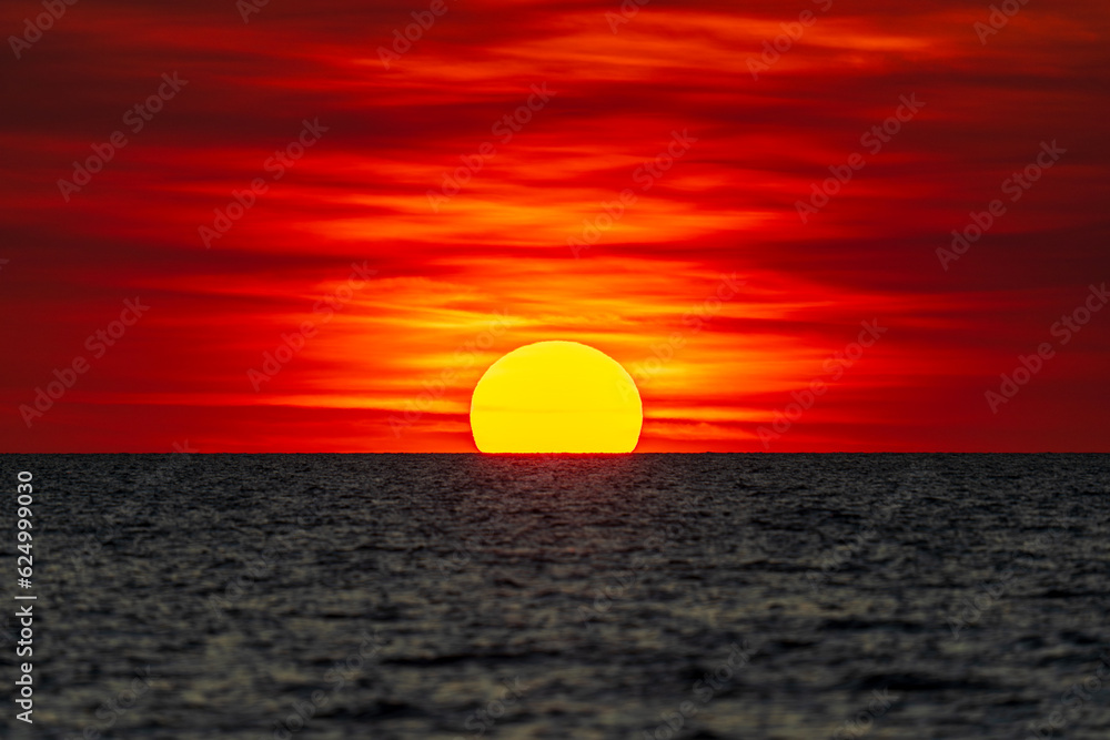 Dramatic sunset on the horizon at Mindil Beach, somewhat resembling the Australian Aboriginal flag. Darwin, Australia.