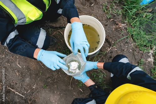 Environmental Engineers Take Water Samples Into Bottles at Rotten Smelly Pond Water Sources, May Be Contaminated by Toxic Waste or Suspicious Pollution Sites.