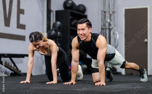 Millennial Asian strong young male and female muscular fitness model athlete couple in sexy sport bra and legging planking bodyweight workout on floor exercise training ready to pushing up in gym