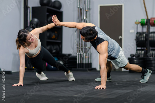 Millennial Asian strong young male and female muscular fitness model athlete couple in sexy sport bra and legging planking bodyweight workout on floor exercise training ready to pushing up in gym