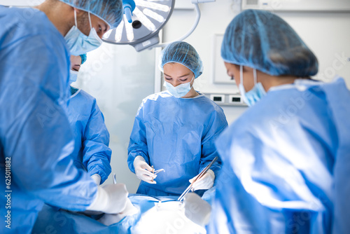 Surgical team performing surgery in modern operation theater,Team of doctors concentrating on a patient during a surgery,Team of doctors working together during a surgery in operating room, photo