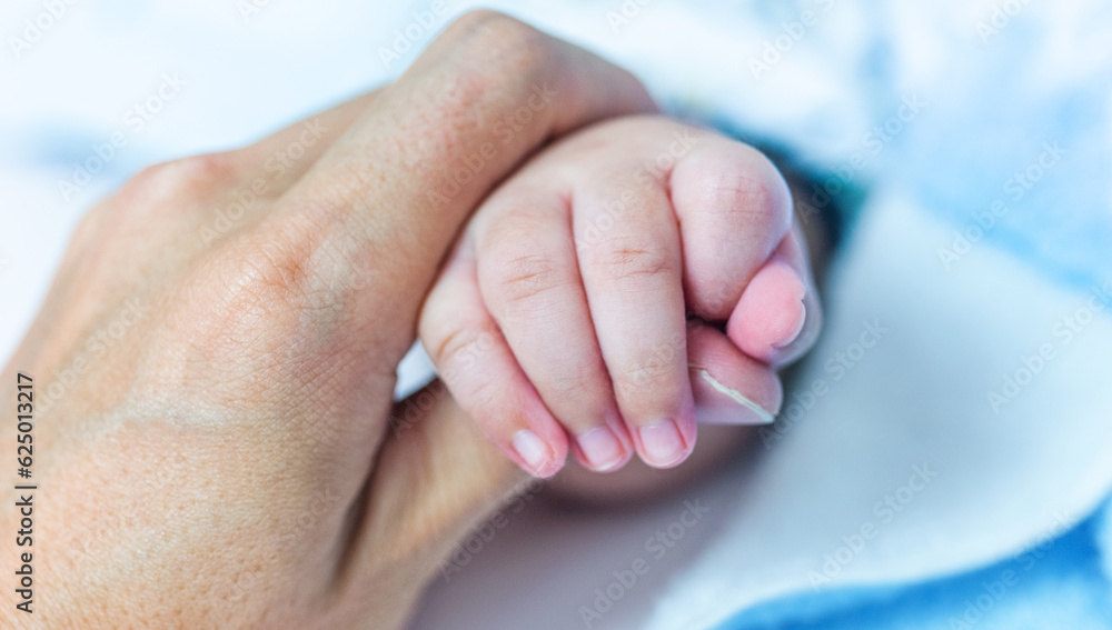 New born asian baby hand holding mother's thumb New born asian baby hand holding mother's thumb