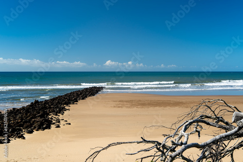 Sandy beach with rock wall extending into the sea. Bargara, Queensland, Australia. photo